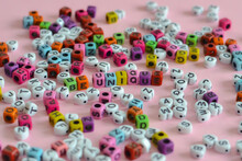 Be Unique Words Written With Colorful Letter Blocks Placed On A Pink Surface Among Many Letter Blocks