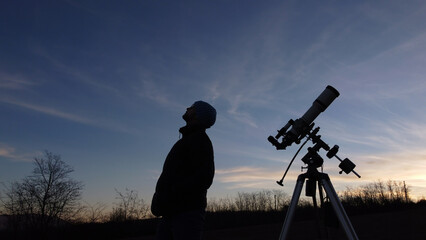 Wall Mural - silhouette of a man, telescope and countryside under evening skies.
