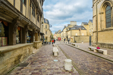 A picturesque street of shops with part of the Cathedral of Our Lady of Bayeux in view in the Calvados department of Normandy, France.