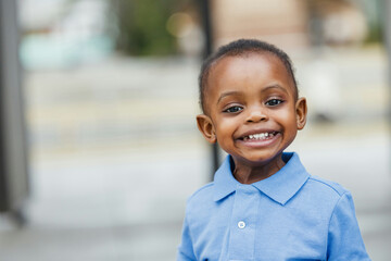 A cute one year old toddler almost preschool age African-American boy with big eyes smiling and looking away with copy space