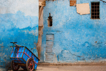 An abandoned blue wagon blends into the blue walls outside the Fes Medina in Morocco