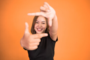 young woman looking at the camera from between fingers forming a frame on isolated background