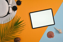Top View Close Up Of Vacation Stuff With Green Leaves, Shells, Coconut, Sunglasses, Beach Hat, And Blank Empty Screen Tablet Ready For Any Advertising Or Text On Two-tone Background;orange Light Blue.