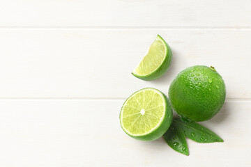 Canvas Print - Flat lay of fresh lime with  cut in half and leaves on white wood background.