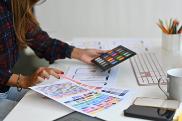 Wall Mural - the close-up of a female designer choosing a color tone for the new media development projects with 