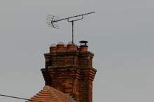 Eight Chimney Pots And TV Aerial On Red Brick Stack