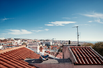 Wall Mural - Traveling by Portugal. Young traveling woman enjoying old town Lisbon view on red tiled roof.