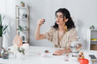 © LIGHTFIELD STUDIOS - Gypsy fortune teller holding magic crystal near candles and magic orb at home.