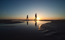 Silhouette Von Zwei Personen Die Während Des Sonnenuntergangs Am Strand Spazieren Gehen
