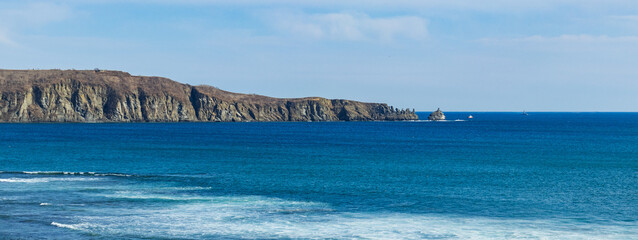 Landscape of the blue sea with a rock along the horizon. Large-format photography of the seascape.