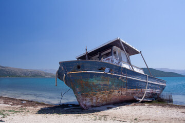 Blue boat wreck on a white sand beach on a Greek Island