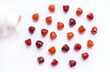 Group of red, orange and purple multivitamin gummies with the bottle isolated on white background. 
