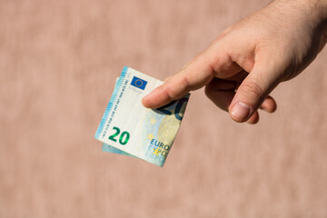 Wall Mural - Closeup of a male hand holding  euros on a brown background