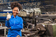 African American Young woman worker in protective uniform operating machine at factory Industrial.People working in industry.Portrait of Female Engineer looking camera at work place.