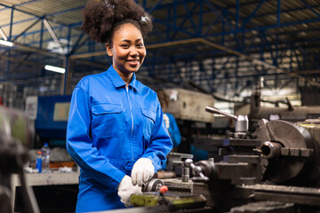 Wall Mural - African American Young woman worker  in protective uniform operating machine at factory Industrial.People working in industry.Portrait of Female  Engineer looking camera  at work place.