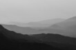 Long exposure grayscale shot of hills in a foggy environment