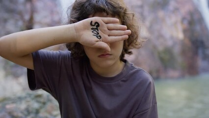 the boy closed his eye with his hand on which the inscription stop is written. the child says no, st
