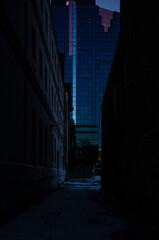 Sticker - Vertical shot of a narrow way leads to the skyscraper at night