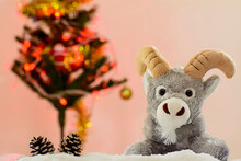 Stuffed Reindeer And Two Pine Cones On Snowflakes With Christmas Tree In The Blurred Background
