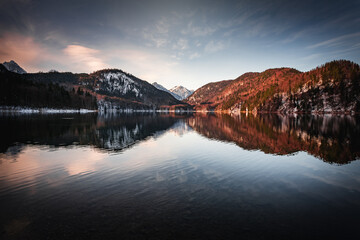 Wall Mural - Scenic shot of a beautiful lake surrounded by snowy forest mountains in a vignette