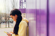 © Dani D.G - Black woman browsing smartphone near wall