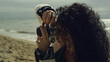 Hispanic girl photographing beach by calm sea. Curly hair woman taking photos.