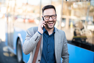 Wall Mural - Business man on bus station, using phone