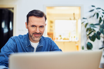 Wall Mural - Closeup picture of middle aged man using laptop at home wearing denim shirt