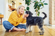 © baranq - Smiling middle aged woman playing with dog at home