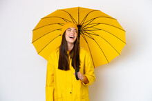 Young Brazilian Woman With Rainproof Coat And Umbrella Isolated On White Background Laughing