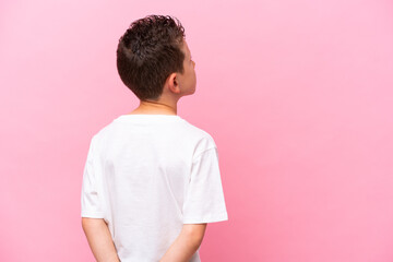 Wall Mural - Little caucasian boy isolated on pink background in back position and looking back