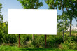 © diesirae - Blank white advertising billboard in fornt of green bushes. There are residential buildings in background.