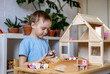 Montessori material. Toddler while playing with big pink dollhouse and having a great time.