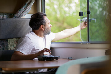 motorhome travel concept. Man controling a drone.a man controls a drone from the window of a motorhome