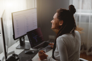 Wall Mural - close up of happy young mixed-race female it worker smiling coding on computer at home