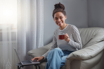 Wall Mural - smiled positive female sitting in chair in living room working browsing on laptop