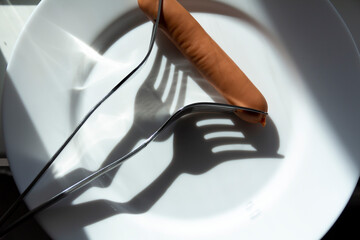 Two people in a family are forced to share a sausage for two with a fork due to lack of money and livelihood due to sanctions and hunger caused by the war.