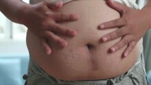 Close Up Of Fat Man Touching Belly And Pinching Excess Fat That Has Around His Waist

