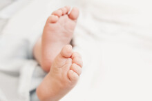Two Baby Feet On The Background Of White Bed Linen. Copy Space. Ukrainian Newborn. Baby's Little Toes. Top View