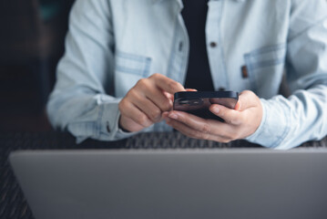 Poster - Casual business man using mobile smart phone and working on laptop computer on table at coffee shop