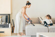 Woman with handheld vacuum cleaning sofa.