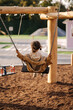 © Aleksandr - Back view of cute little girl swing on a swing in the specially designated place in the park. Softner from sawdust underfoot