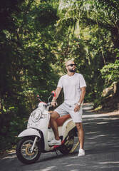 Wall Mural - Stylish young man and his motorbike on the road in the jungle