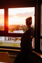 Pregnant Woman Contemplating The Sunset From The Window