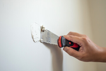 Man repairing crack white wall with spatula