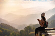 © Kittiphan - Happy young woman traveler drinking coffe, relaxing and looking at the beautiful sunrise on the top of mountain