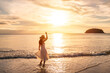 Leinwandbild Motiv Young woman traveler dancing and enjoying beautiful Sunset on the tranquil beach, Travel on summer vacation concept