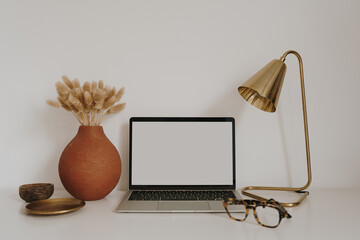 Wall Mural - Laptop with blank copy space screen on table with stationery on table against white wall. Minimalist home office workspace. Mockup template