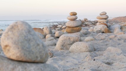 Wall Mural - Rock balancing on pebble beach, Monterey 17-mile drive, California coast, USA. Stable pyramid stacks of round stones, sea ocean water waves crashing at sunset. Serenity harmony, calm zen meditation.