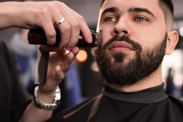 Professional hairdresser working with client in barbershop, closeup